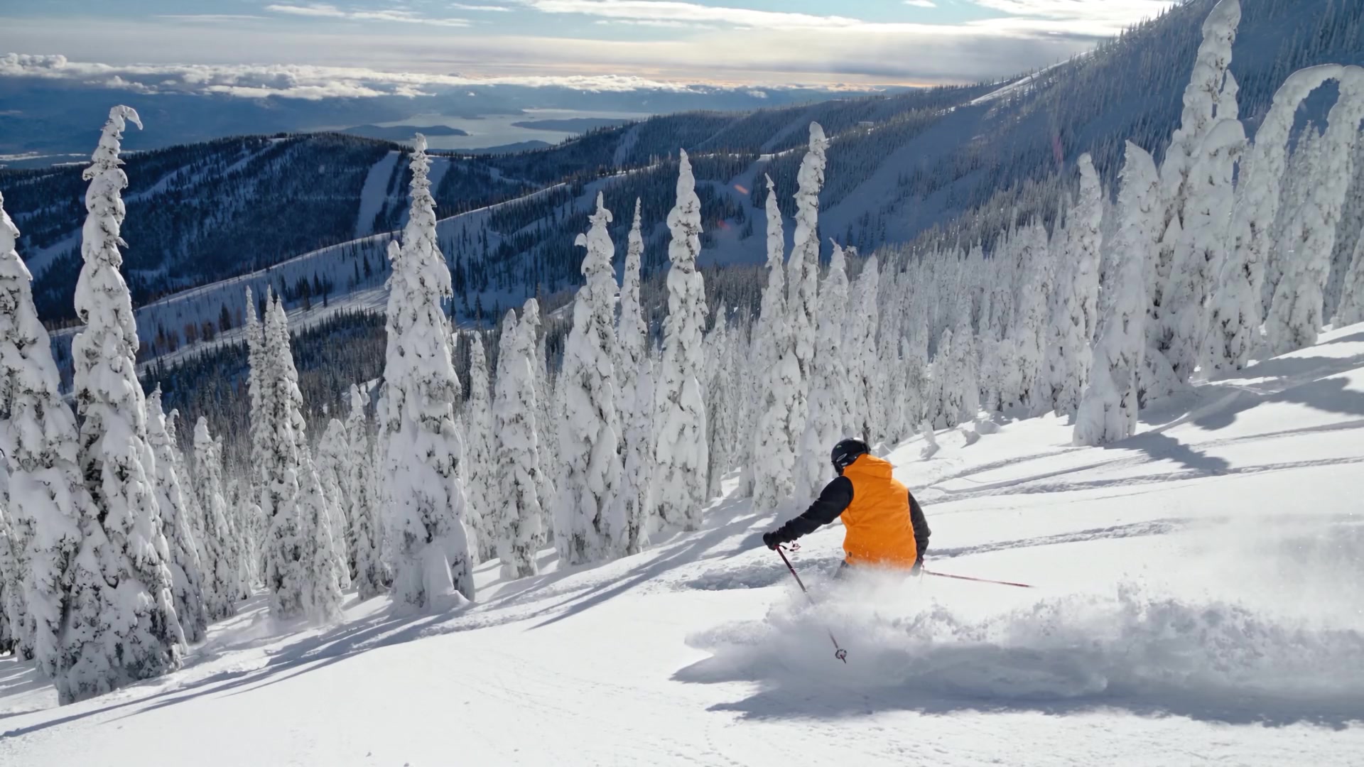 A skier at rest on Schweitzer Mountain, Lake Pend Oreille in the distance